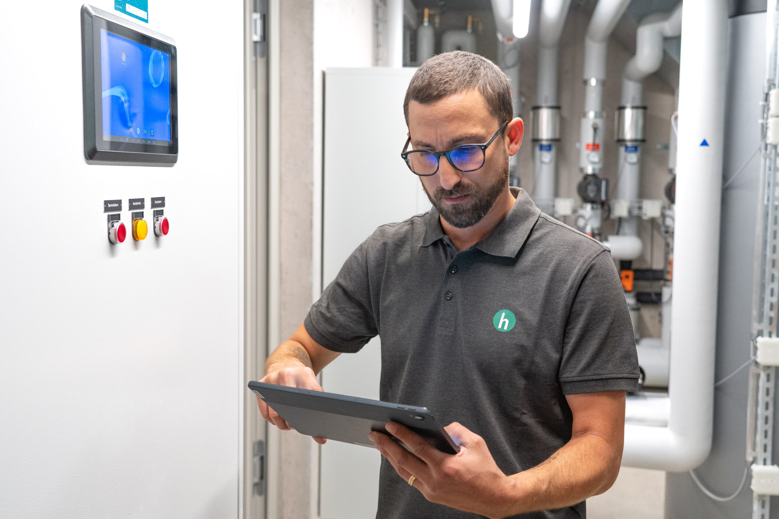 Hauswart der Honegger AG mit einem Tablet in der Hand in einem Heizungsraum